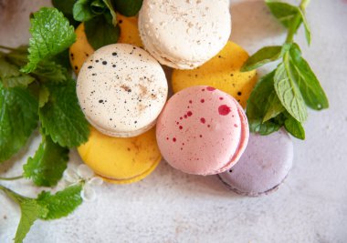 Çeşitli nane yapraklarıyla süslenmiş birkaç lezzetli badem kurabiyesi, hafif bir arka planda. Metin ve yiyecek arkaplanı için boşluk kopyala.