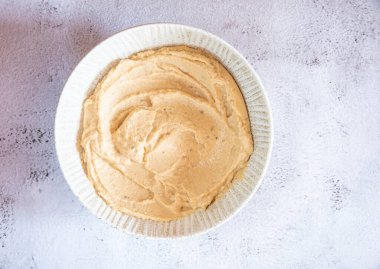 Açık gri bir zemin üzerinde humus ve nohut olan kalın bir tabak..