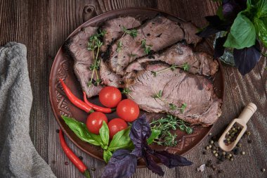 Baharatlı otlarla süslenmiş killi bir tabakta dilimlenmiş et parçaları. Yemek arkaplanı.