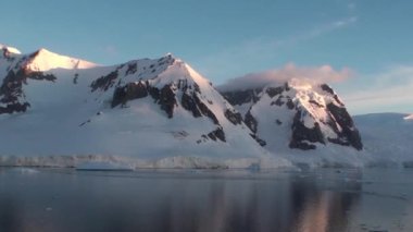 Antarktika. Antarktika 'daki karlı dağların ve buzlu kıyıların manzarası. Ayna yansımalı güzel mavi buzdağı açık okyanusta yüzüyor.