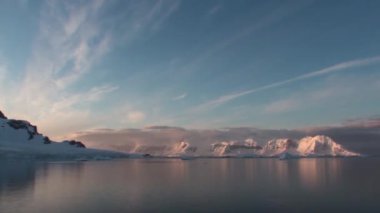 Antarktika. Antarktika 'daki karlı dağların ve buzlu kıyıların manzarası. Ayna yansımalı güzel mavi buzdağı açık okyanusta yüzüyor.