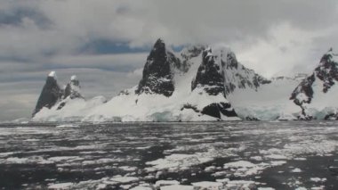 Antarktika. Antarktika 'daki karlı dağların ve buzlu kıyıların manzarası. Ayna yansımalı güzel mavi buzdağı açık okyanusta yüzüyor.