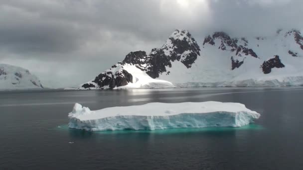 Antartide. Paesaggio di montagne innevate e spiagge ghiacciate in Antartide. Bellissimo iceberg blu con riflesso a specchio galleggia in mare aperto — Video Stock