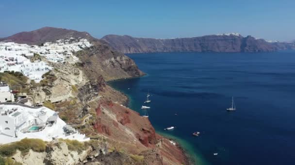 Famose case bianche e cupole blu sul bordo della scogliera. Oia, Santorini. Grecia. Vista aerea. — Video Stock
