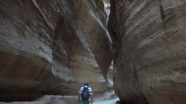Bir gezgin taş bir kanyon boyunca yürür. Kızıl kayalardan oluşan güzel bir kanyonun arasından geçen inanılmaz bir yol.