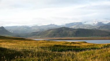 İzlanda. Denizin ve volkanik bazalt kayaların üzerinde renkli, ılık bir gün batımı. Dalgalar kayaya çarpıyor.