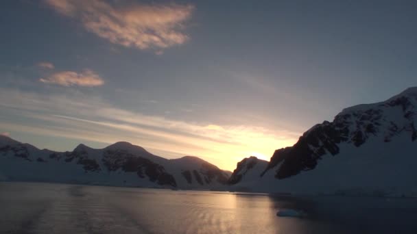 Solnedgång i Antarktis, med lugnt havsvatten som reflekterar vackert och pittoreskt orange, gult och blått och berg med klippiga stränder — Stockvideo