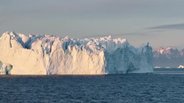 Baffin Adası 'nın nefes kesen sahil güzelliğini tecrübe edin. Parlayan buzdağlarının dingin sularla buluştuğu yer şafak vakti dağların arkası..