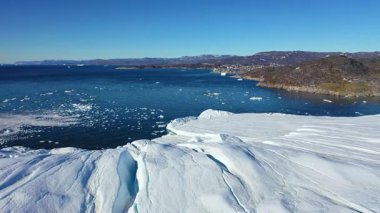 Güzel buzdağları, etrafındaki dağları yansıtan sakin sularda yüzer. Güneşli bir günde Grönland 'ın doğasının güzelliğini yansıtan bu sakin manzara eşsiz özelliklerini gözler önüne seriyor..