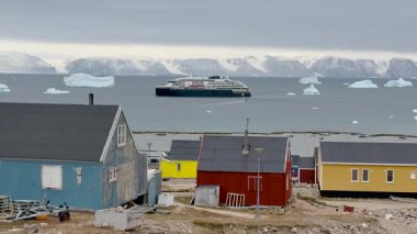 Parlak renkli evler okyanusa yakın, buzdağlarıyla çevrili. Bulutlu gökyüzü bu sakin Grönland manzarasına eşsiz bir ortam ekler. Doğa ve kültür burada güzel bir şekilde harmanlanır..