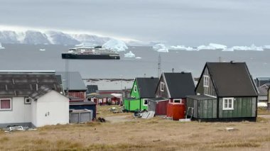 Parlak renkli evler okyanusa yakın, buzdağlarıyla çevrili. Bulutlu gökyüzü bu sakin Grönland manzarasına eşsiz bir ortam ekler. Doğa ve kültür burada güzel bir şekilde harmanlanır..