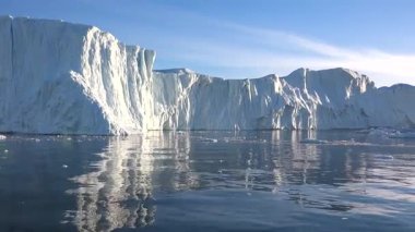 Buzdağları berrak mavi kutup sularında huzur içinde sürüklenirler. Güneş, buzdan yansıyan parlak bir şekilde parlıyor. Kuzey Kutbu 'ndaki doğa harikalarının güzel bir manzarası..