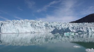 Buzdağları berrak mavi kutup sularında huzur içinde sürüklenirler. Güneş, buzdan yansıyan parlak bir şekilde parlıyor. Kuzey Kutbu 'ndaki doğa harikalarının güzel bir manzarası..