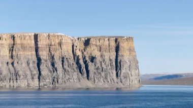 Bu sakin kutup bölgesinde sersemletici uçurum kulesi. Parlak mavi gökyüzü bu uzak ve huzurlu manzaranın doğal güzelliğini arttırır..