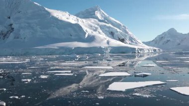 Antarktika 'daki kutup buzu, sakin sulara ve sürüklenen buzdağlarına yansıyan parlak güneş ışığında görüldüğü gibi, iklim değişikliği nedeniyle yavaş yavaş eriyor..