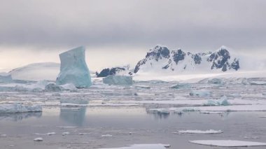 Antarktika 'daki kutup buzu, sakin sulara ve sürüklenen buzdağlarına yansıyan parlak güneş ışığında görüldüğü gibi, iklim değişikliği nedeniyle yavaş yavaş eriyor..