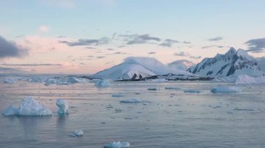 Antarktika 'daki kutup buzu, sakin sulara ve sürüklenen buzdağlarına yansıyan parlak güneş ışığında görüldüğü gibi, iklim değişikliği nedeniyle yavaş yavaş eriyor..
