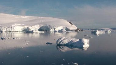 Antarktika 'daki kutup buzu, sakin sulara ve sürüklenen buzdağlarına yansıyan parlak güneş ışığında görüldüğü gibi, iklim değişikliği nedeniyle yavaş yavaş eriyor..