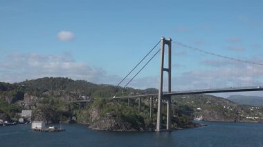 Huzurlu bir nehri geçen olağanüstü bir köprünün nefes kesici görüntüsü. Yeşil yemyeşil tepeler ve antika bir ada Norveç 'in büyüleyici manzarasını güzelleştiriyor..