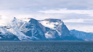 Nefes kesici uçurumlar bir yaz günü sakin suların üzerinde görkemli bir şekilde yükselir. Berrak gökyüzü, kar kaplı zirveleriyle Kuzey Kutbu 'nun güzelliğini sergiliyor..