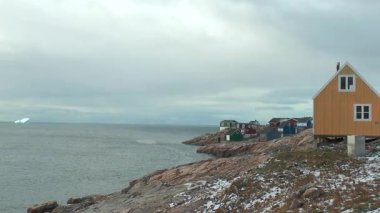 Grönland 'da kar ve buzla kaplı kayalık bir sahilde renkli evler bulunur. Okyanus dalgaları kara parçalarına çarpıyor. Bu uzak yerdeki basit yaşamı gösterir..