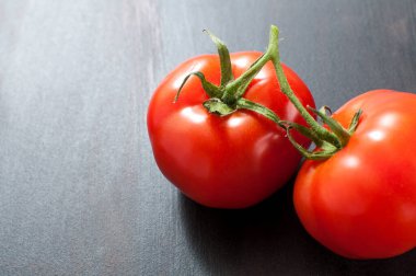 Koyu gri arkaplanlı iki taze organik domates. Kopyalama uzaylı yatay görüntü.