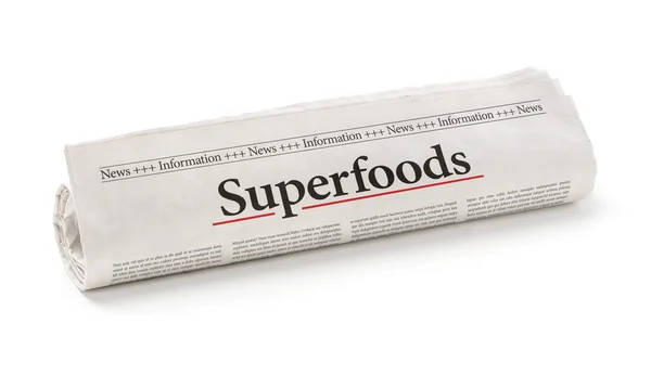 Rolled newspaper with the headline Superfoods — Stock Photo, Image