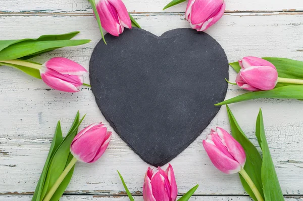 Ροζ τουλίπες με μια κενή καρδιά σχήμα πίνακα κιμωλίας — Φωτογραφία Αρχείου