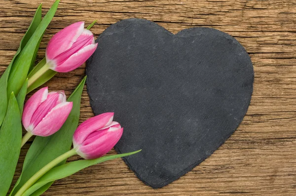 Roze tulpen op een houten achtergrond met een hart-vormige teken — Stockfoto