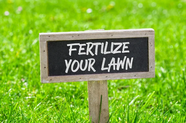 Sign on a green lawn - Fertilize your lawn — Stock Photo, Image