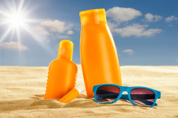 Vários produtos sunsreen na areia — Fotografia de Stock