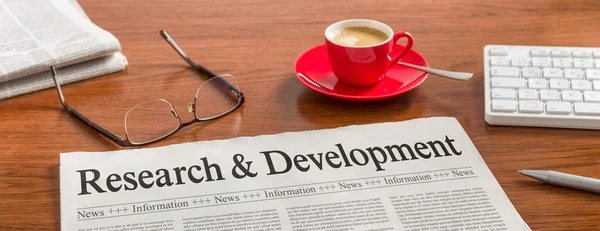 A newspaper on a wooden desk - Research and Development — Stock Photo, Image