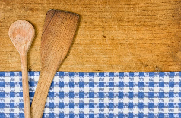 Wooden background with a blue checkered tablecloth and wooden spoon — Stock Photo, Image
