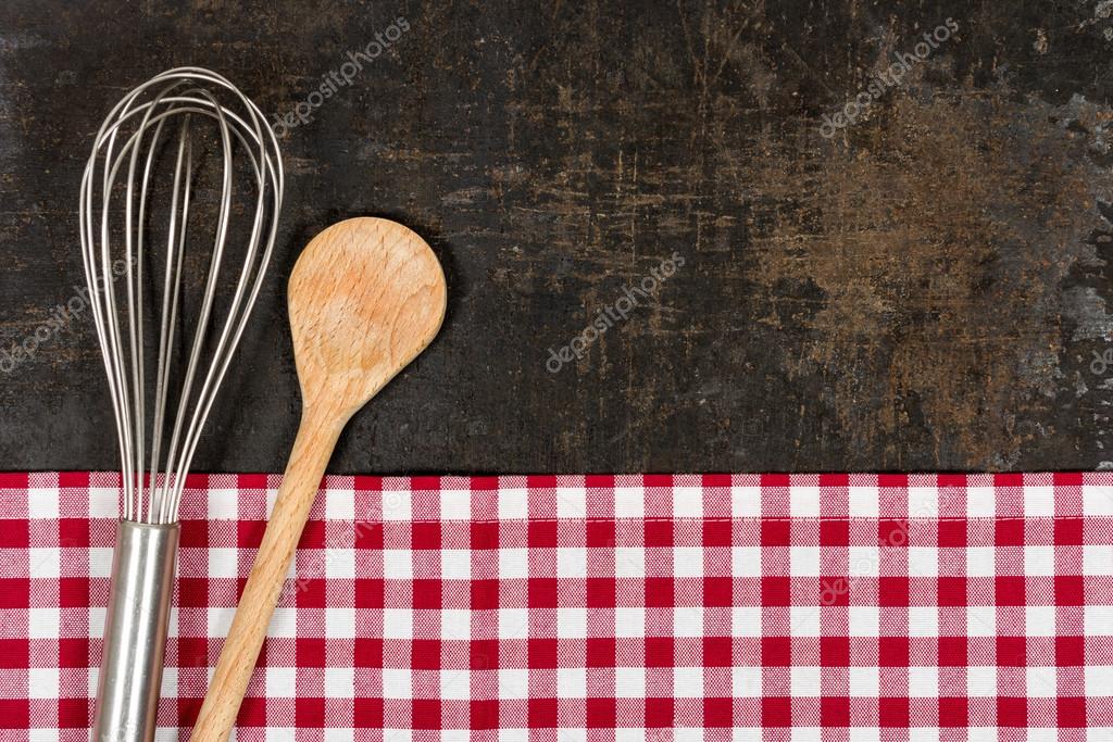 Old baking tray with red checkered table cloth and baking utensils