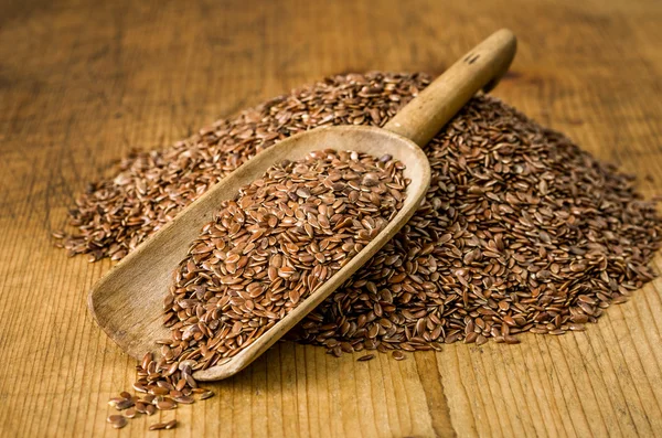 Wooden scoop with flax seeds — Stock Photo, Image