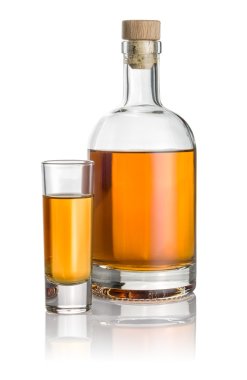 Bottle and high shot glass filled with amber liquid clipart