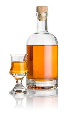 Bottle and schnapps glass filled with amber liquid clipart