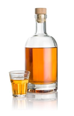 Bottle and beveled shot glass filled with amber liquid clipart