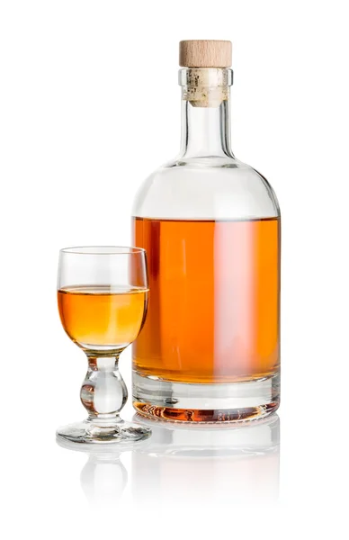 Flasche und Glasbecher gefüllt mit bernsteinfarbener Flüssigkeit — Stockfoto