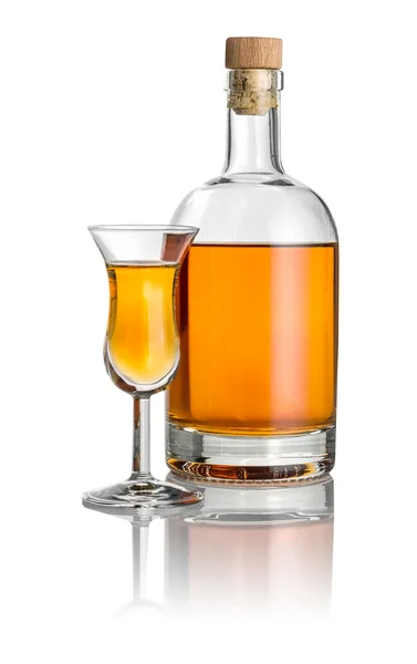 Fles en hoge stengel glas gevuld met amberkleurige vloeistof — Stockfoto