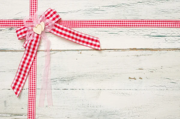 Red ribbons and a bow on a white wooden background — Stock Photo, Image