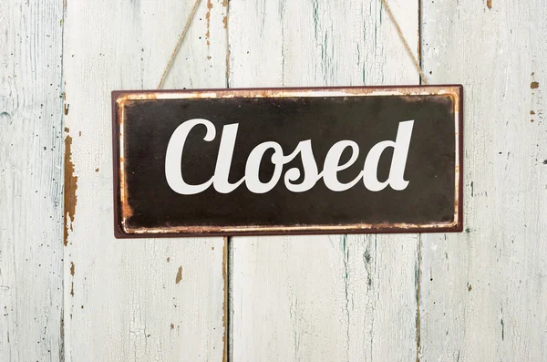 Old metal sign in front of a white wooden wall - Closed — Stock Photo, Image