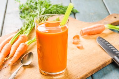 A glass of carrot juice with fresh carrots clipart