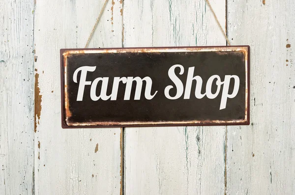 Vecchio segno di metallo di fronte a un muro di legno bianco - Farm Shop — Foto Stock