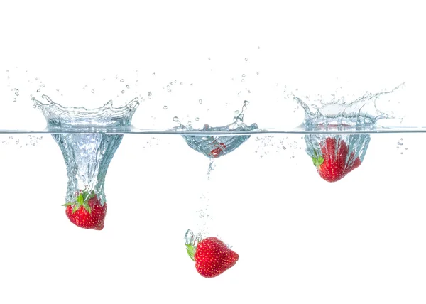Fresh strawberries falling into water with splashes — Stock Photo, Image