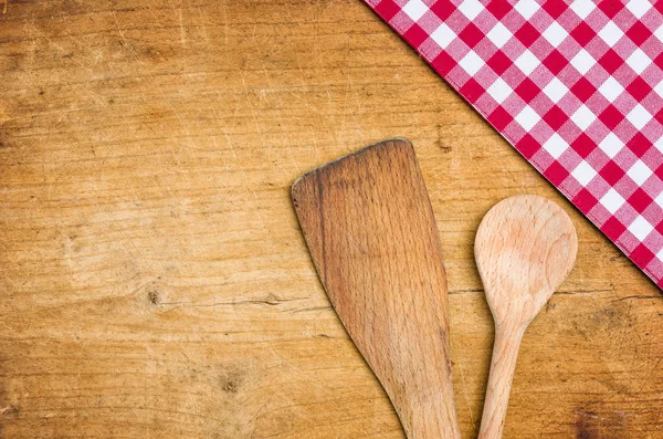 Kochlöffel mit einer karierten Tischdecke auf einem hölzernen Hintergrund — Stockfoto