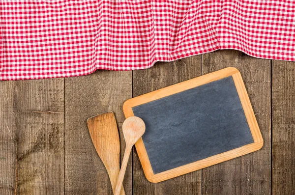 Chalkboard e colheres de madeira com uma toalha de mesa quadriculada vermelha — Fotografia de Stock