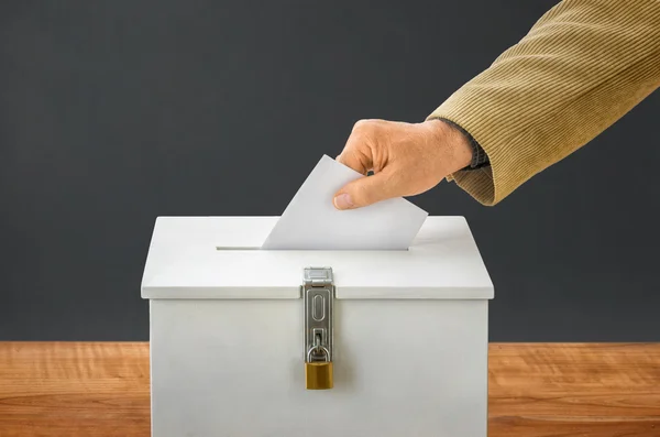 Un homme met un bulletin de vote dans une urne — Photo