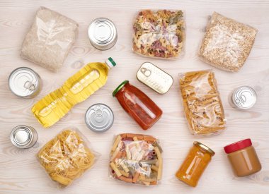 Makarna, pirinç, yağ, fıstık ezmesi, konserve yiyecekler, reçel ve diğer bağışları beyaz ahşap masaya, üst görünüm