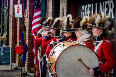 Saint Charles, MO-- 19 Aralık 2018; Kurtuluş Ordusu aktörleri tarihi Fife and Drum Corp grubunu koleksiyon kettle yakınında koloni elbisesi içinde yeniden yarattılar..